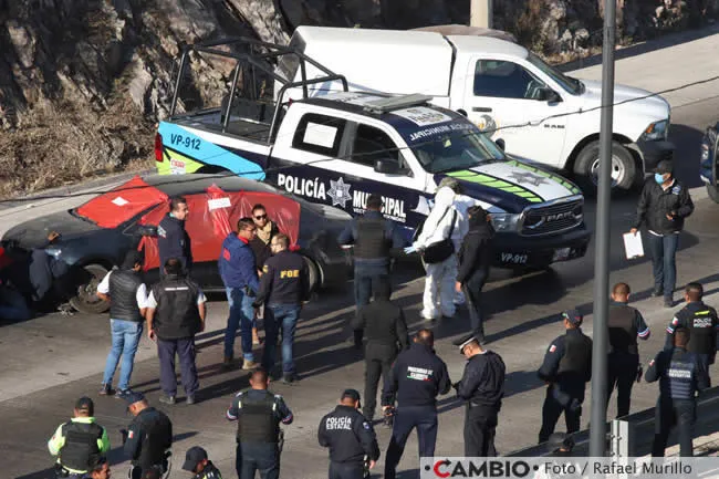 Autoridades junto a automóvil que contenía los restos humanos de siete hombres.